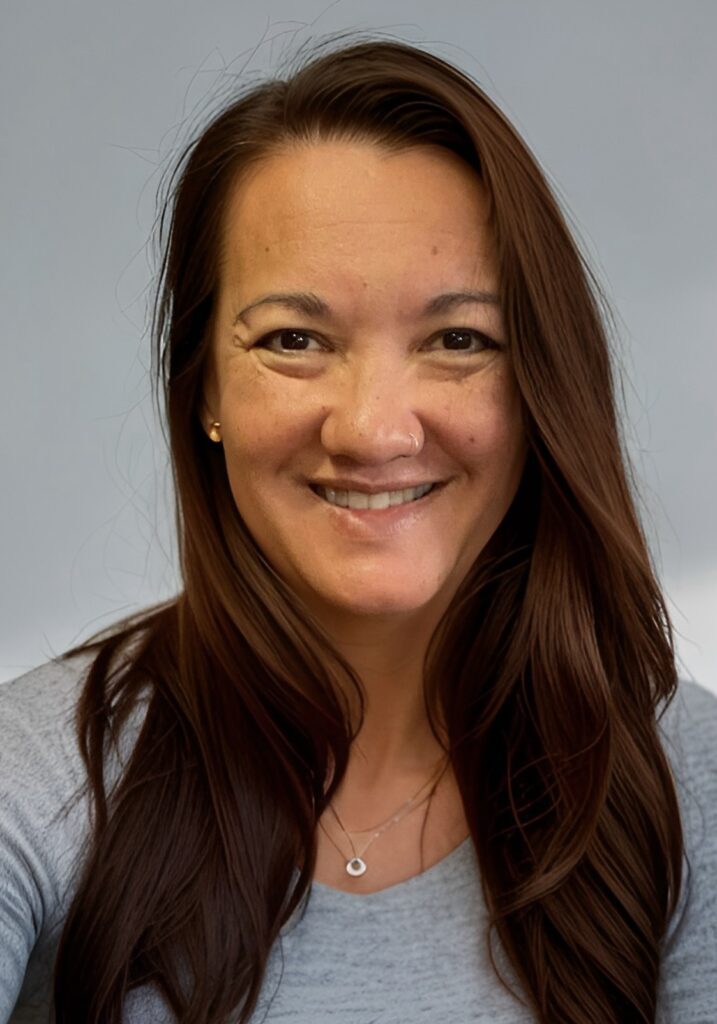 A woman with long brown hair smiles for the camera.